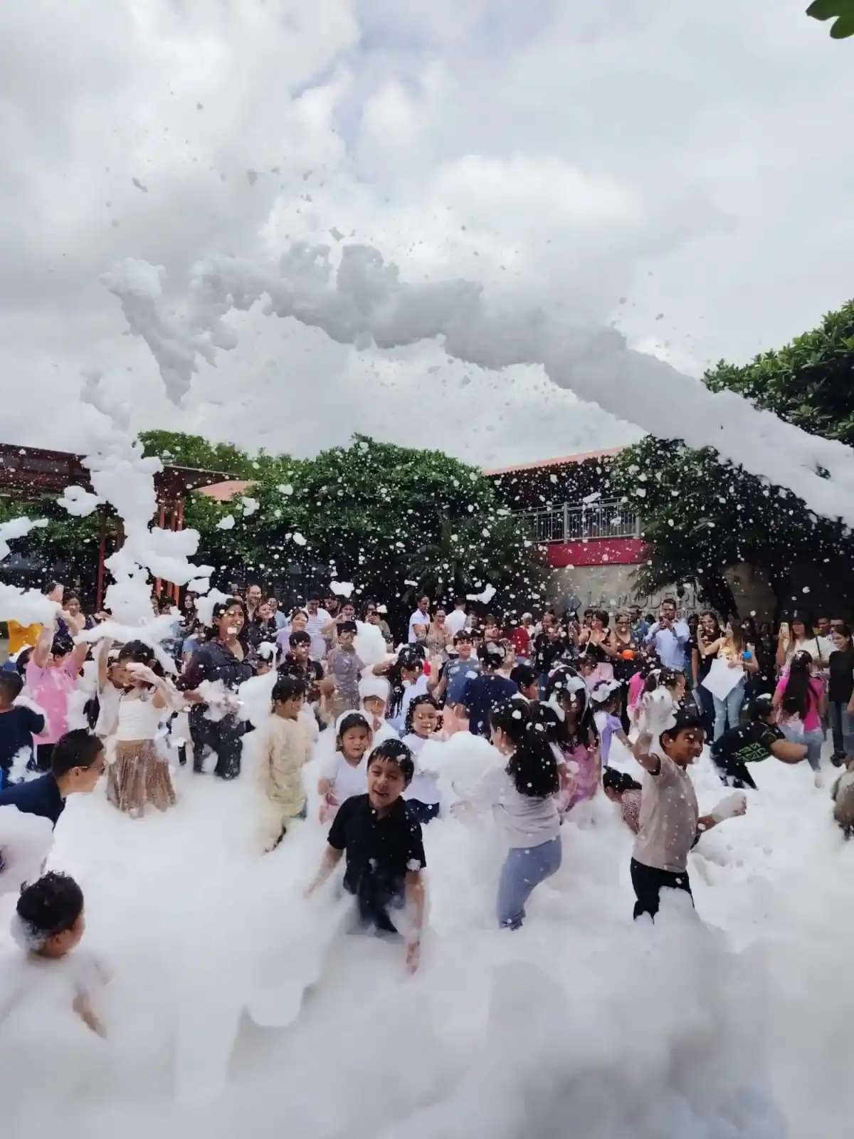 Niños y familias jugando entre montañas de espuma en el patio de un colegio de Guayaquil