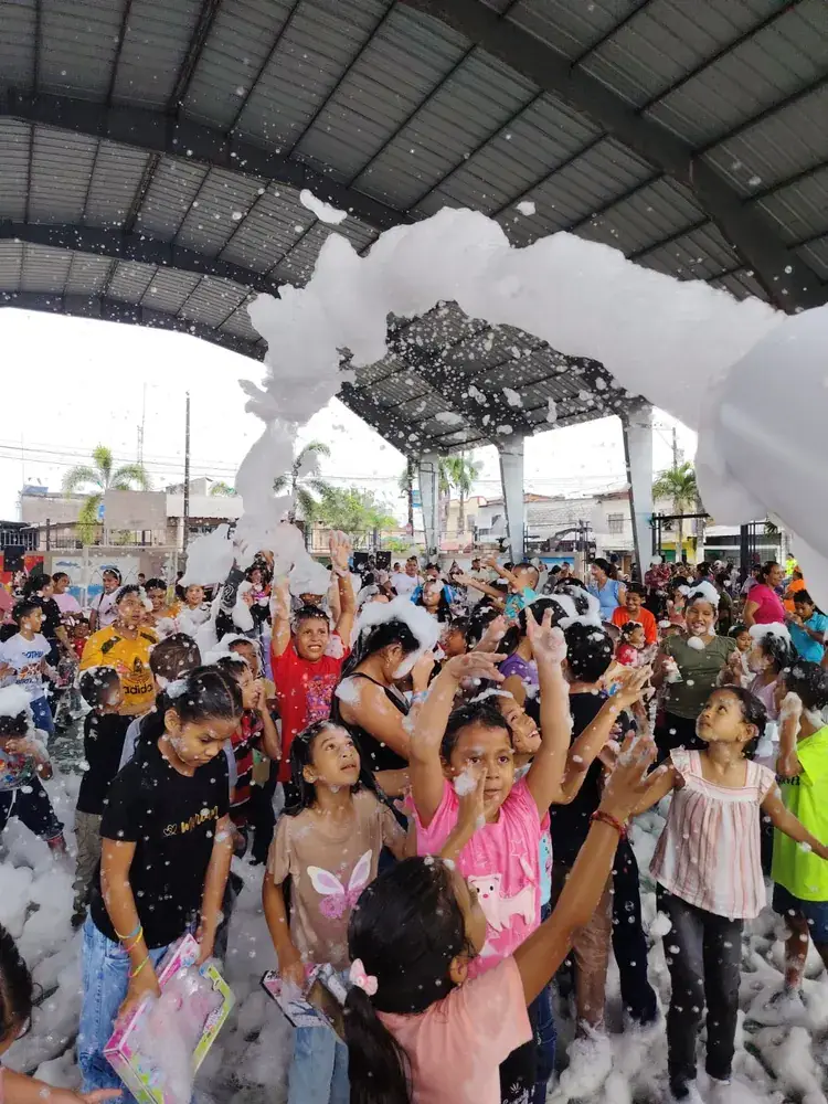 Niños celebrando bajo el chorro del cañón de espuma en una cancha cubierta